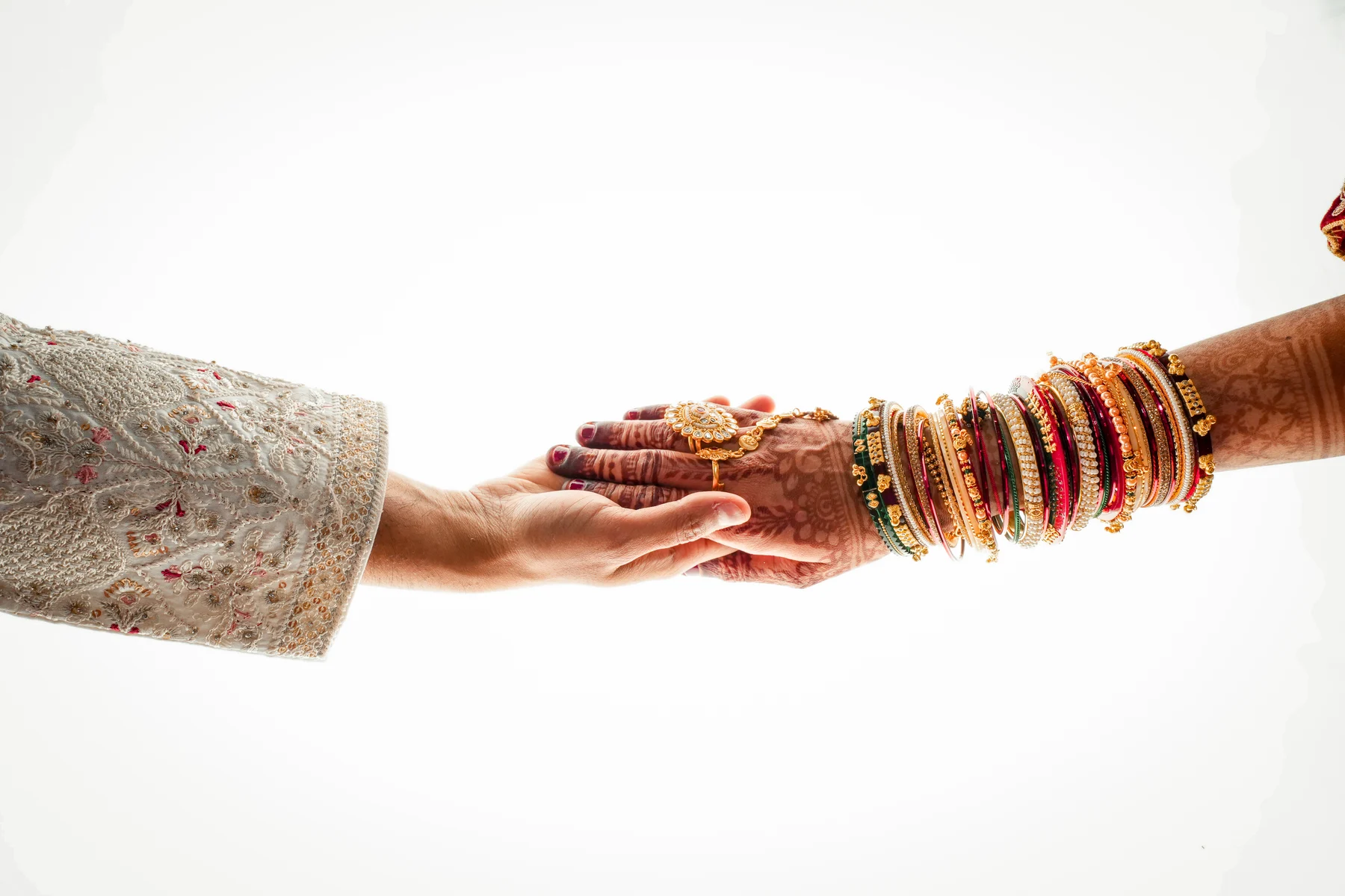 A bride places her mehndi-adorned hand into her partner’s hand