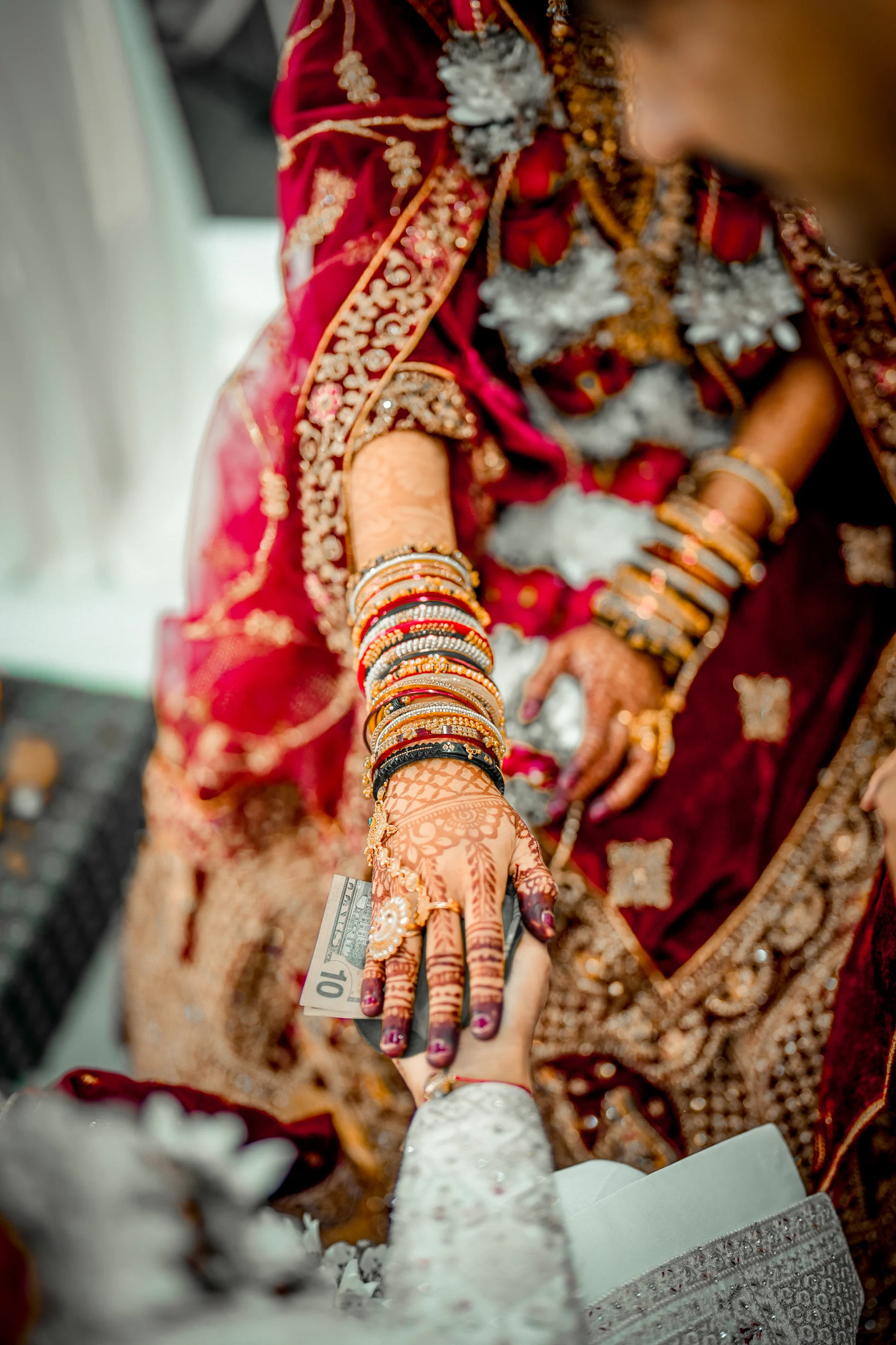 A groom gently holds his bride’s mehndi-adorned hand during their wedding ceremony